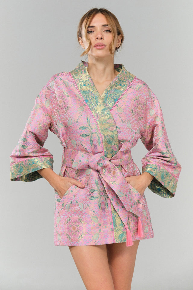 Woman wearing a pink floral robe against a gray background